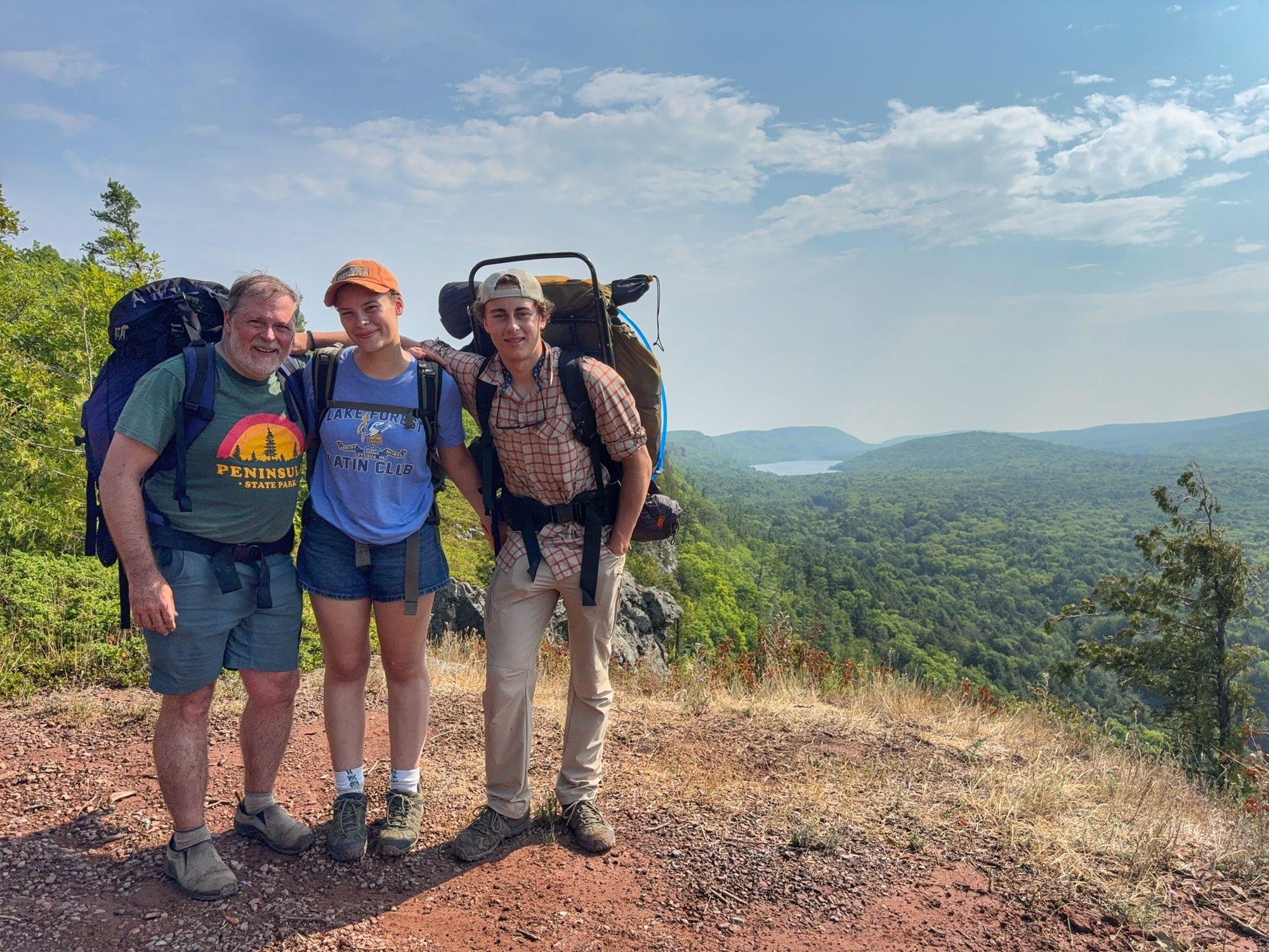 Our family with backpacks at an overlook above a forested valley and lake